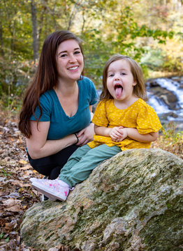 mother and daughter on hike at water fall with girl sticking out her tongue