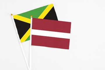 Latvia and Jamaica stick flags on white background. High quality fabric, miniature national flag. Peaceful global concept.White floor for copy space.