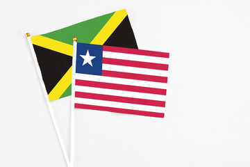 Liberia and Jamaica stick flags on white background. High quality fabric, miniature national flag. Peaceful global concept.White floor for copy space.