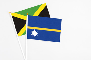 Nauru and Jamaica stick flags on white background. High quality fabric, miniature national flag. Peaceful global concept.White floor for copy space.