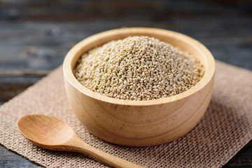 Raw quinoa seed in bowl and spoon on wooden background
