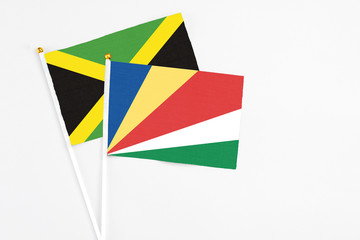 Seychelles and Jamaica stick flags on white background. High quality fabric, miniature national flag. Peaceful global concept.White floor for copy space.