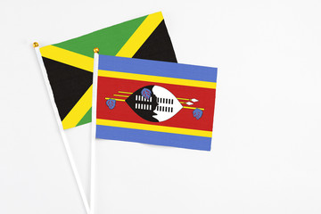 Swaziland and Jamaica stick flags on white background. High quality fabric, miniature national flag. Peaceful global concept.White floor for copy space.