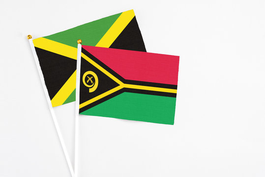 Vanuatu and Jamaica stick flags on white background. High quality fabric, miniature national flag. Peaceful global concept.White floor for copy space.