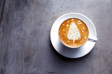 Tasty cappuccino with Christmas tree latte art on grey concrete background.