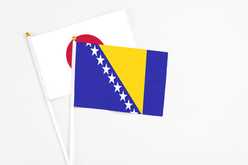 Bosnia Herzegovina and Japan stick flags on white background. High quality fabric, miniature national flag. Peaceful global concept.White floor for copy space.