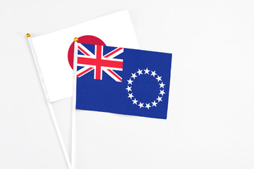 Fototapeta premium Cook Islands and Japan stick flags on white background. High quality fabric, miniature national flag. Peaceful global concept.White floor for copy space.
