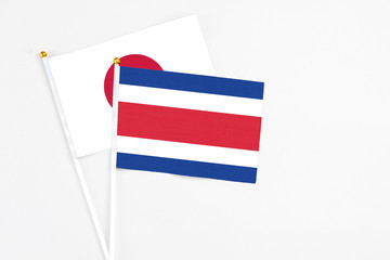 Costa Rica and Japan stick flags on white background. High quality fabric, miniature national flag. Peaceful global concept.White floor for copy space.