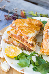 Lobiani - traditional baked Georgian pie with lobio beans and filo puff pastry. On plate with lemon slice, green rucola leaves and garlic. Homemade.