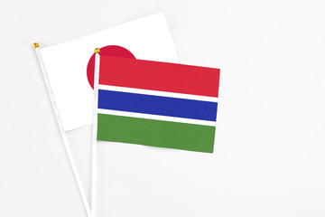 Gambia and Japan stick flags on white background. High quality fabric, miniature national flag. Peaceful global concept.White floor for copy space.