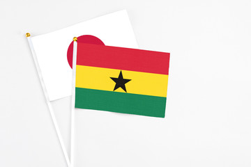 Ghana and Japan stick flags on white background. High quality fabric, miniature national flag. Peaceful global concept.White floor for copy space.