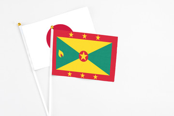 Grenada and Japan stick flags on white background. High quality fabric, miniature national flag. Peaceful global concept.White floor for copy space.