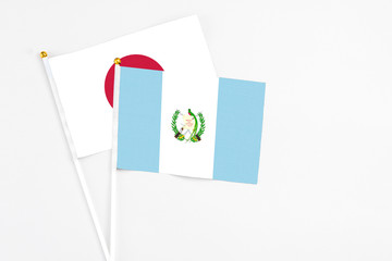 Guatemala and Japan stick flags on white background. High quality fabric, miniature national flag. Peaceful global concept.White floor for copy space.