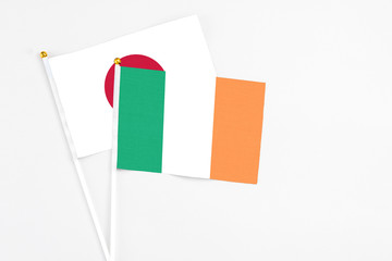 Ireland and Japan stick flags on white background. High quality fabric, miniature national flag. Peaceful global concept.White floor for copy space.