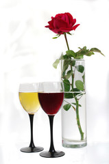 Two glasses of white and red wine and a rose in a glass vase. Isolated on white.