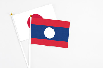 Laos and Japan stick flags on white background. High quality fabric, miniature national flag. Peaceful global concept.White floor for copy space.