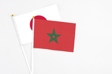 Morocco and Japan stick flags on white background. High quality fabric, miniature national flag. Peaceful global concept.White floor for copy space.