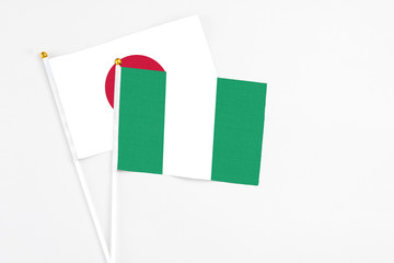 Nigeria and Japan stick flags on white background. High quality fabric, miniature national flag. Peaceful global concept.White floor for copy space.