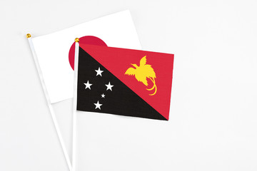 Papua New Guinea and Japan stick flags on white background. High quality fabric, miniature national flag. Peaceful global concept.White floor for copy space.