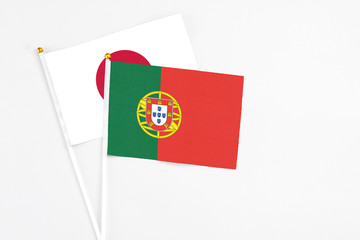 Portugal and Japan stick flags on white background. High quality fabric, miniature national flag. Peaceful global concept.White floor for copy space.