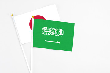 Saudi Arabia and Japan stick flags on white background. High quality fabric, miniature national flag. Peaceful global concept.White floor for copy space.