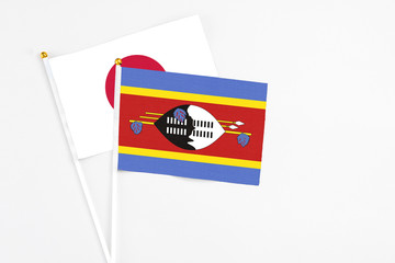 Swaziland and Japan stick flags on white background. High quality fabric, miniature national flag. Peaceful global concept.White floor for copy space.