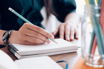 Close up female hands with pen writing on notebook.