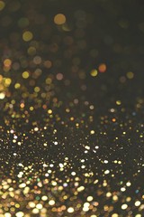 Golden bokeh background. Golden glitter on a black background.Festive New Year and Christmas shiny...