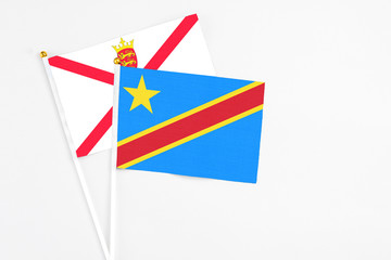 Obraz premium Congo and Jersey stick flags on white background. High quality fabric, miniature national flag. Peaceful global concept.White floor for copy space.