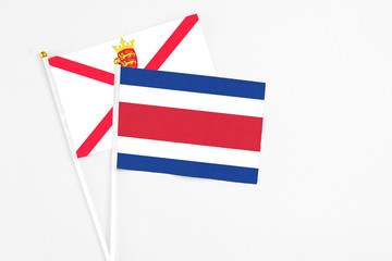 Costa Rica and Jersey stick flags on white background. High quality fabric, miniature national flag. Peaceful global concept.White floor for copy space.