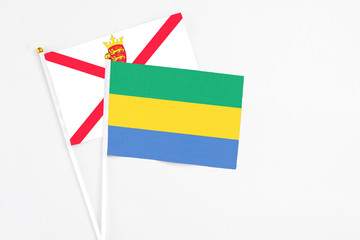 Gabon and Jersey stick flags on white background. High quality fabric, miniature national flag. Peaceful global concept.White floor for copy space.