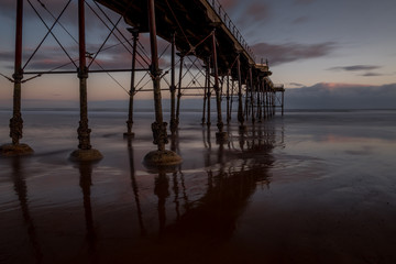 Fototapeta na wymiar Sunrise Under Santburn Pier at low tide on the beach