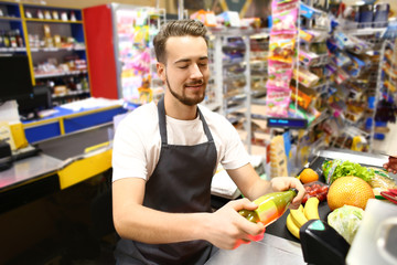 Male cashier checking out goods in supermarket
