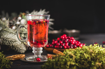 Hot cranberry drink with fresh cranberries on dark background