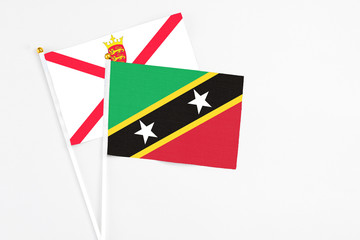 Saint Kitts And Nevis and Jersey stick flags on white background. High quality fabric, miniature national flag. Peaceful global concept.White floor for copy space.