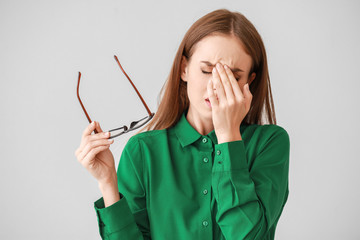 Young woman suffering from headache on light background