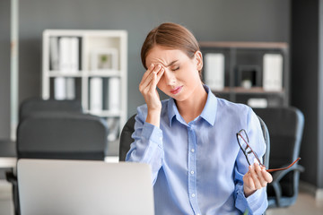 Young woman suffering from headache in office