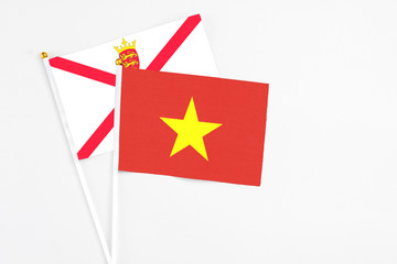 Vietnam and Jersey stick flags on white background. High quality fabric, miniature national flag. Peaceful global concept.White floor for copy space.