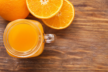 Mason jar of fresh orange juice on wooden table