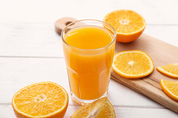 Glass of fresh orange juice on white table