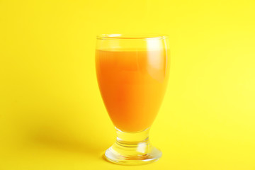 Glass of fresh orange juice on color background