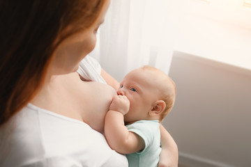 Young woman breastfeeding her baby at home