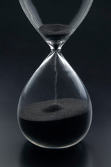 Hourglass on a dark background. Time is money. Business solutions in time.