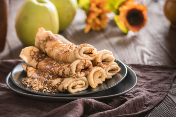Delicious plain pancakes with caramel sauce and nuts on wooden background