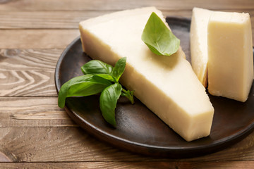 Plate with tasty Parmesan cheese on wooden background
