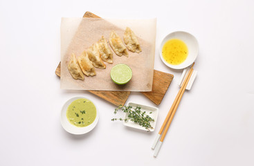 Tasty Japanese gyoza and sauces on white background