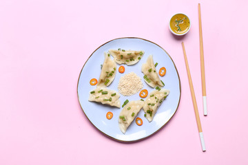Plate with tasty Japanese gyoza and sauce on color background