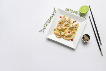 Fototapeta na wymiar Plate with tasty Japanese gyoza and sauce on white background