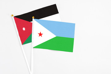 Djibouti and Jordan stick flags on white background. High quality fabric, miniature national flag. Peaceful global concept.White floor for copy space.