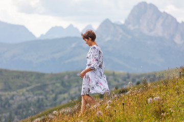 Fototapeta premium Girl in a dress on a background of mountains. Mountain valley of the Alps, Dolomites. Summer sunny day
